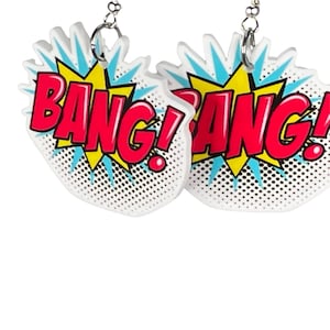 May include: A pair of white earrings with a comic book style "Bang!" design. The earrings are red, yellow, and blue.