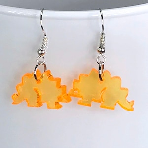May include: A pair of orange dinosaur shaped earrings with silver hooks.