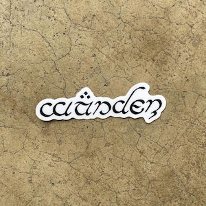 May include: A white sticker with the word "cäirden" written in black cursive lettering.