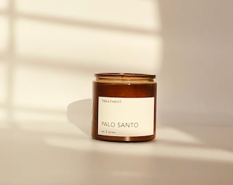 May include: A brown glass jar candle with a white label featuring the text TREATMENT. PALO SANTO 7 OZ | SOY WAX. The candle has a visible wick at the top and is contained within a cylindrical vessel, presenting a simple and functional design.