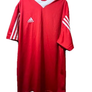 K&ouml;nnte beinhalten: Rotes Adidas Fu&szlig;balltrikot mit wei&szlig;en Akzenten. Mit V-Ausschnitt und Adidas-Logo auf der Brust. Wei&szlig;e Streifen auf den &Auml;rmeln. Ein klassisches Sport-Top.