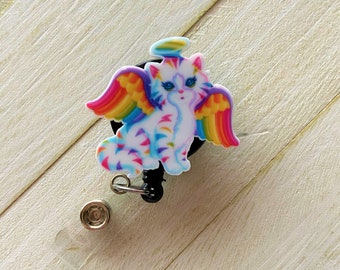 May include: A rainbow cat with angel wings and a halo, a black retractable badge reel with a silver clip and a silver button.