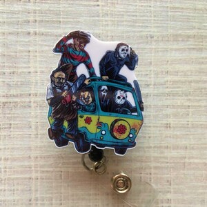 Può includere: Un portachiavi colorato con un furgone verde e blu con un gruppo di personaggi di film horror, tra cui Freddy Krueger, Michael Myers, Jason Voorhees e Ghostface.