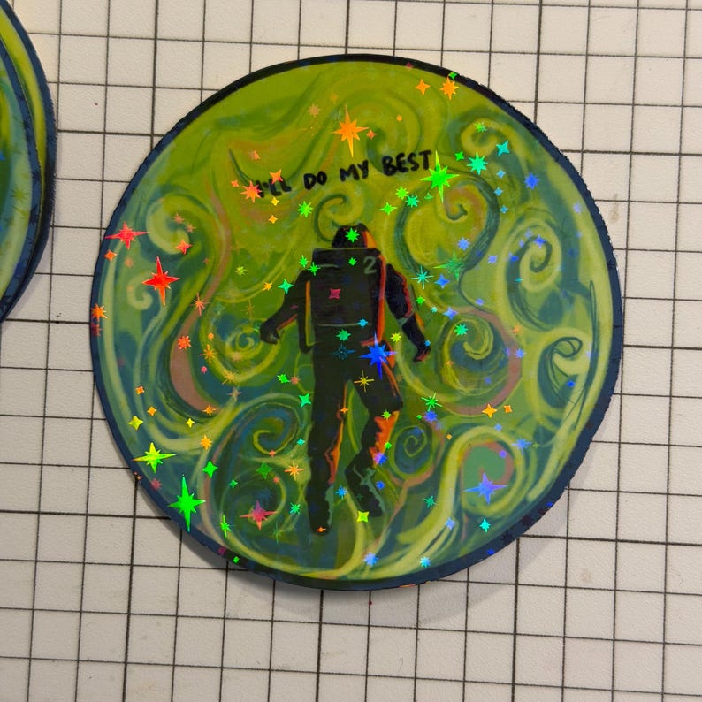 May include: Circular sticker with a green and blue swirling background, a silhouetted astronaut figure, and the text "I'll do my best." The sticker has holographic accents with colorful starbursts.