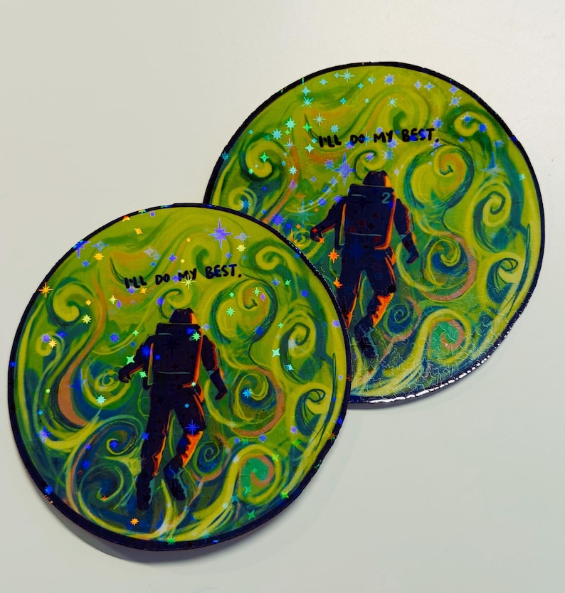 May include: Two circular stickers with a vibrant design. Each features a silhouetted astronaut against a swirling yellow and green background with the text "I'll do my best." Holographic accents add sparkle.