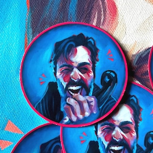 Può includere: Adesivi rotondi con un ritratto di una persona che ride con la barba. Il ritratto è ambientato su uno sfondo blu con un bordo rosa. L'opera d'arte utilizza colori vivaci e pennellate espressive.