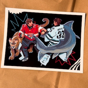 May include: Illustration of two hockey players in jerseys, one red and one white, facing off with a cougar and a shark. The red jersey has the number 72, and the white jersey has the number 33. The background is black with lightning bolt designs.