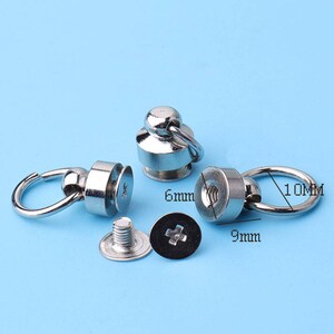 Könnte beinhalten: Drei silberne Metall-Druckknöpfe mit einer Schlaufe und einer Schraube. Die Druckknöpfe haben einen Durchmesser von 6 mm, 9 mm und 10 mm.