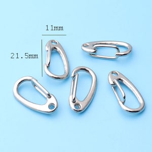 May include: Five silver-toned metal keychains with a D-ring opening. Each keychain measures 21.5 mm in length and 11 mm in width.