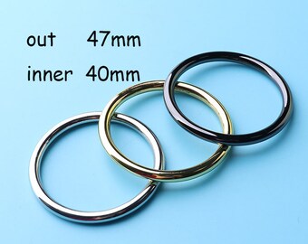 May include: Three metal rings in silver, gold, and black. The rings are stacked on top of each other. The outer ring measures 47mm and the inner ring measures 40mm.