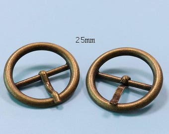 May include: Two gold-toned metal belt buckle rings, each with a center bar, measuring 25mm in diameter.