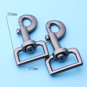 Puede incluir: Dos mosquetones giratorios de metal plateado de 37 mm de ancho y 80 mm de largo. Los mosquetones están diseñados para sujetarse a correas, collares u otros artículos.