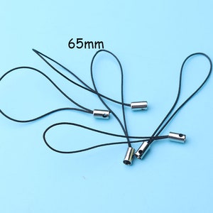 May include: Several black lanyards with silver-colored metal ends, each with a loop. The text "65mm" is visible, indicating the length of the lanyards. The background is a solid light blue.