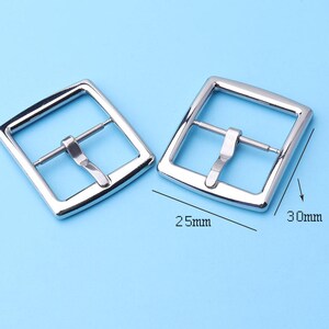 May include: Two silver metal belt buckle closures. The buckle on the left measures 2.5 inches wide and the buckle on the right measures 3 inches wide.