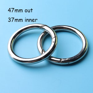 May include: Two silver metal rings, one inside the other. The larger ring has an outer diameter of 47 mm and an inner diameter of 37 mm.