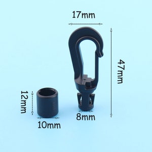 Puede incluir: Un gancho de plástico negro y un anillo de plástico negro. El gancho mide 4,7 cm de alto, 1,7 cm de ancho y 0,8 cm de grosor. El anillo mide 1,2 cm de alto, 1 cm de ancho y 1 cm de grosor.