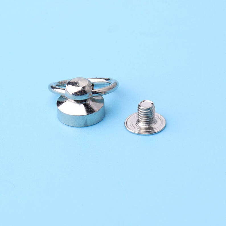 May include: Silver metal ring with a round knob and a screw-on base. The ring is attached to a screw with a flat head.
