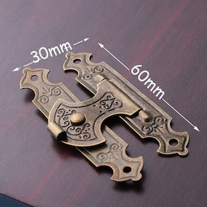 以下が含まれることがあります： 装飾的なデザインと小さなノブが中央にある、60mm×30mmのアンティークブラスラッチ。