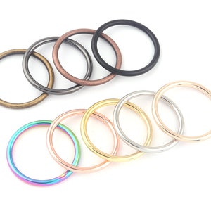 May include: Assortment of eight metal jump rings in various colors, including rainbow, gold, silver, and black. The rings are arranged in a circle on a white background.