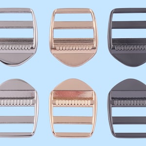Puede incluir: Seis hebillas deslizantes de metal en tres acabados diferentes: plata, oro y negro. Cada hebilla tiene tres barras horizontales y un borde texturizado.