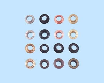 Op de afbeelding: Assortiment van 12 metalen oogjes in verschillende kleuren, waaronder zilver, goud, zwart en koper. De oogjes zijn gerangschikt in een rasterpatroon op een lichtblauwe achtergrond.