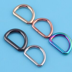 May include: Five metal D-rings in different colors: gold, rose gold, black, silver, and iridescent.