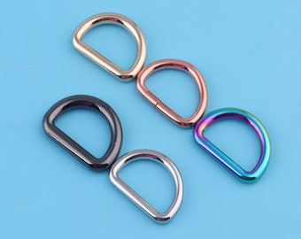 May include: Five metal D-rings in different colors: gold, rose gold, black, silver, and iridescent.