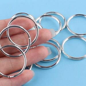 May include: A set of silver key rings, all of the same size and shape, arranged on a blue surface.