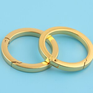 May include: Two gold-coloured metal key rings with a spring-loaded clasp. The rings are interlocked.