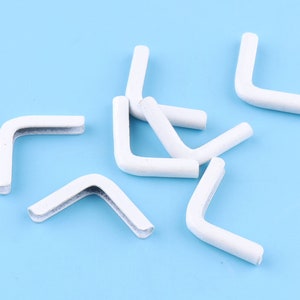 May include: A group of white plastic corner protectors, designed to protect furniture from damage. These corner protectors are ideal for use on tables, desks, and other furniture.