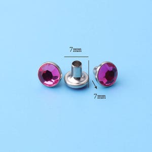 May include: Three pink rhinestone studs with silver settings. Each stud measures 7 mm in diameter.