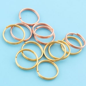 Pode incluir: Uma coleção de chaveiros de ouro e ouro rosa. Os chaveiros estão dispostos em círculo sobre um fundo azul.