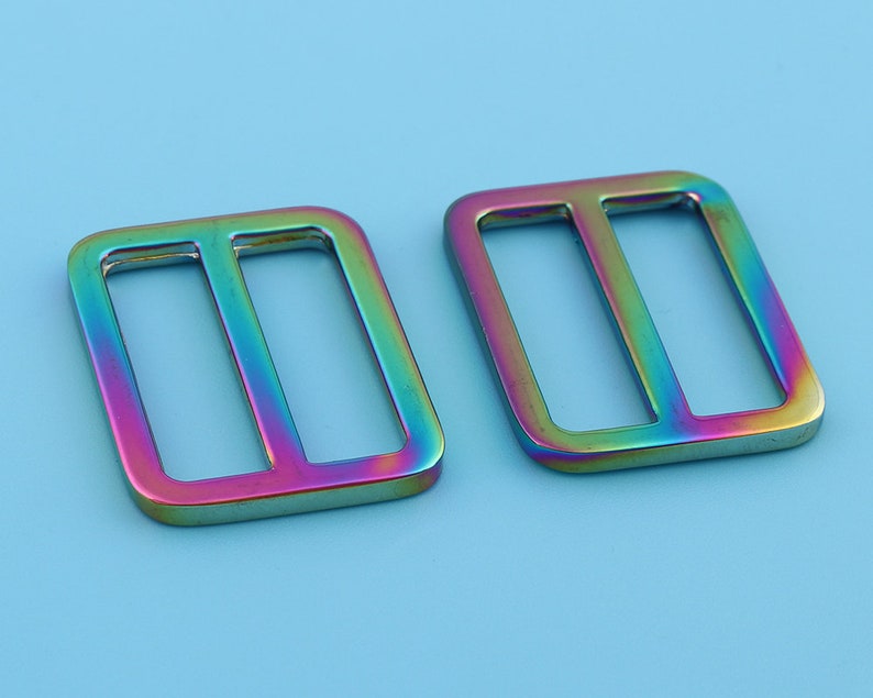 May include: Two iridescent metal slider buckles. The buckles are rectangular with a rounded edge and have a double-loop design.