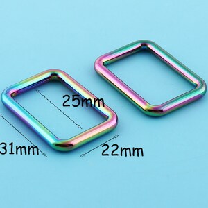May include: Two iridescent metal rectangular rings, one measuring 31mm by 25mm and the other 22mm by 25mm.