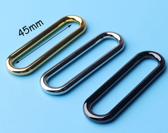 May include: Three oval-shaped metal rings in gold, silver, and black. The rings are 45mm in length.