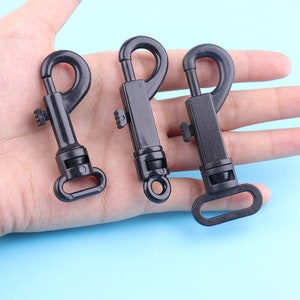 May include: Three black plastic dog leash clips. The clips have a spring-loaded mechanism and a swivel hook.