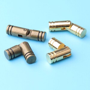May include: Four cabinet hinges, two gold and two bronze, with a swivel design. The hinges are made of metal and have a polished finish.
