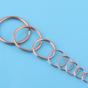 May include: A set of eight rose gold key rings of varying sizes, arranged in descending order from largest to smallest.