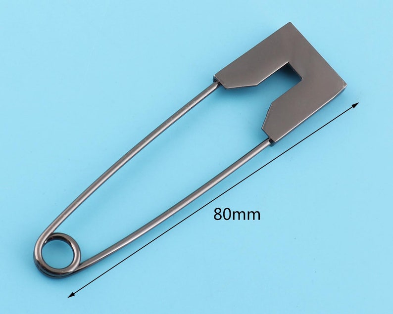 Peut inclure: Une &eacute;pingle &agrave; nourrice argent&eacute;e avec une grande t&ecirc;te rectangulaire. L'&eacute;pingle mesure 80 mm de long.