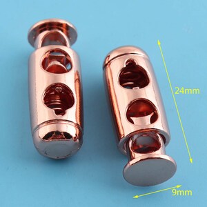 Puede incluir: Dos cierres de palanca de oro rosa, cada uno mide 24 mm de largo y 9 mm de diámetro. Los cierres tienen un mecanismo de resorte y dos agujeros para cordón o cuerda.