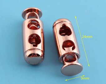 May include: Two rose gold toggle clasps, each measuring 24 mm in length and 9 mm in diameter. The clasps have a spring-loaded mechanism and two holes for cord or rope.