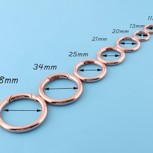 May include: A set of eight gold-toned metal rings with different diameters, ranging from 11 mm to 38 mm. Each ring has a spring-loaded clasp.
