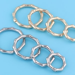 May include: Two sets of interlocking metal rings with a bamboo-like design. The rings are in silver and gold tones.