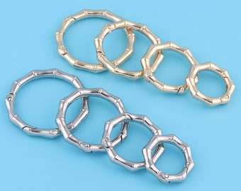 May include: Two sets of interlocking metal rings with a bamboo-like design. The rings are in silver and gold tones.