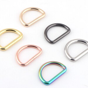 May include: Six different colored metal D-rings. The rings are gold, rose gold, silver, black, and iridescent.