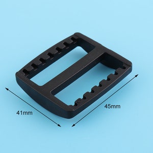 Puede incluir: Hebilla de plástico negro con dos aberturas rectangulares. La hebilla mide 41 mm por 45 mm.