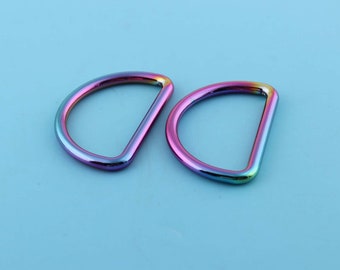 May include: Two iridescent metal D-rings, each with a smooth, rounded finish. The rings are a vibrant mix of pink, blue, and purple.
