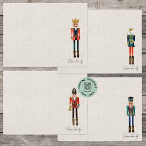 May include: Set of four placemats featuring a watercolor illustration of a nutcracker soldier. Each placemat has a different nutcracker design and the text "Downs Family" printed on the bottom. The placemats are made of machine washable poly linen.