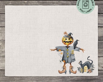 May include: A gray and orange Halloween scarecrow with a pumpkin head, a black crow on its shoulder, and a black cat to the right. The scarecrow is wearing a gray jacket with buttons and has a spider web on its arm. The background is a white linen fabric with the text "Machine Washable Poly Linen" in a circle.