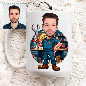 May include: White ceramic mug with a cartoon illustration of a man in a mechanic's uniform holding a spanner. The illustration is set against a workshop backdrop. A small portrait of a man is in the upper left corner.